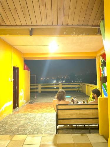 dos personas sentadas en un banco mirando la vista en Over the Moon hostel, en Ban Houayxay
