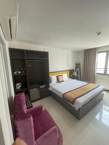 um quarto com uma cama grande e uma cadeira roxa em Tokia hotel nha trang em Nha Trang