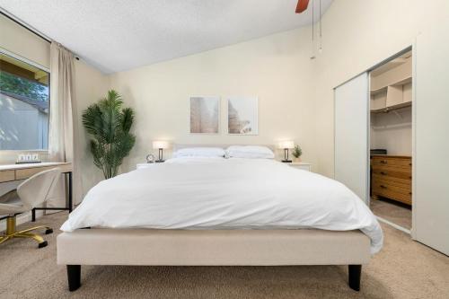 a white bedroom with a large bed and a desk at Delightful Home w Fireplace Patio Fire Pit in Roseville