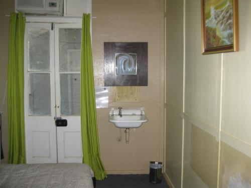 baño con lavabo y ventana con cortinas verdes en Australian Hotel Winton Budget Hotel Accommodation, en Winton