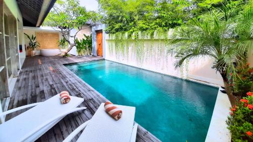 a swimming pool in a backyard with two white chairs at The Decks Bali in Legian