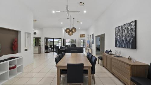 a dining room and living room with a table and chairs at Canal Serenity Retreat in Banksia Beach