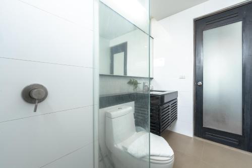 a white bathroom with a toilet and a glass door at G1 Touch Blue Sky in Kamala Beach