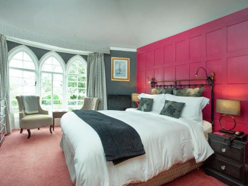 a bedroom with a large bed with a pink headboard at Lifton Hall - Sycamore in Lifton