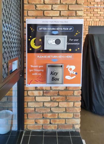 a sign on a brick wall with a key box at Archer Park Motel in Rockhampton