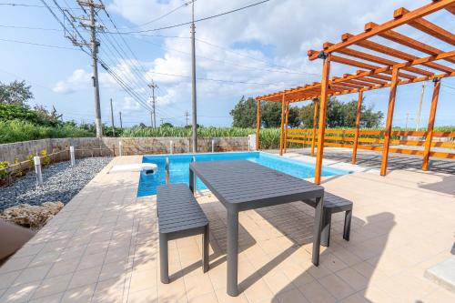 a picnic table and benches next to a pool at private house noko in Miyako Island