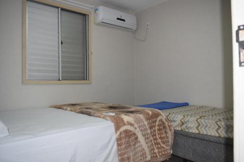 um pequeno quarto com 2 camas e uma janela em APARTAMENTO 2 QUARTOS COMPLETAMENTE MOBILIADO COM GARAGEM em São Borja