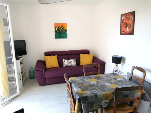 sala de estar con mesa y sofá púrpura en Studio a Guethary a 150 m de la plage avec jardin clos, en Guéthary