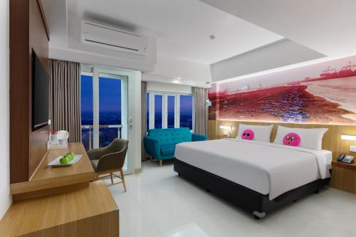 a hotel room with a large bed and a desk at favehotel Cilacap in Cilacap