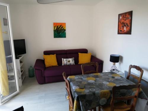 sala de estar con mesa y sofá púrpura en studio guéthary - 100 m plages et centre a pieds, en Guéthary