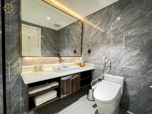 een badkamer met een toilet, een wastafel en een spiegel bij Cửa Đông Luxury Hotel in Vinh