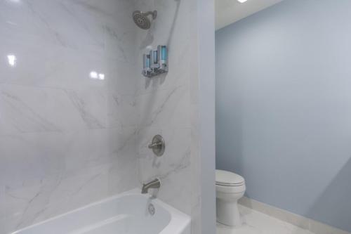 a white bathroom with a tub and a toilet at Sea La Vie Beach Oceanfront Patio Pet Friendly in Jacksonville Beach