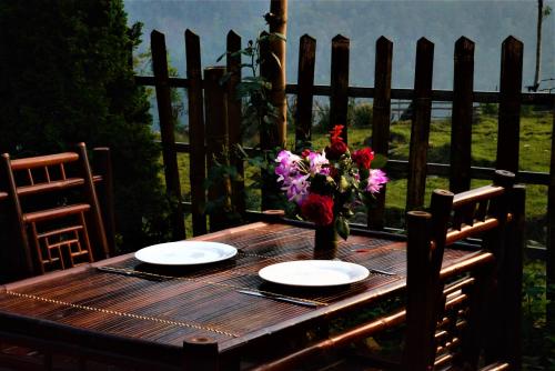 a wooden table with two plates and a vase of flowers at Lee's Charm Homestay in Sa Pa
