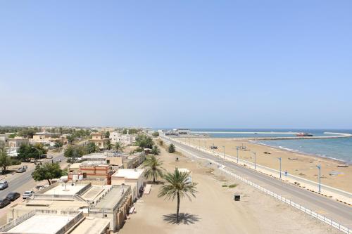索哈尔مارينا للغرف الفندقية的享有棕榈树海滩和建筑的景色