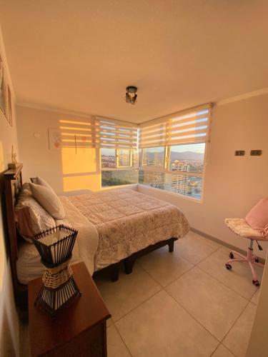 ein Schlafzimmer mit einem Bett und einem großen Fenster in der Unterkunft Hermoso y amplio Departamento frente al mar in Coquimbo
