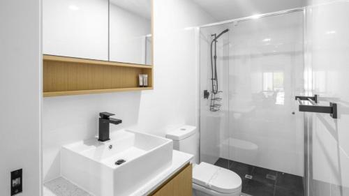 a white bathroom with a sink and a shower at Modern Unit On The Marina in Sandstone Point