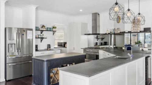 a large kitchen with white cabinets and stainless steel appliances at Opulent Canal-Front Retreat in Banksia Beach