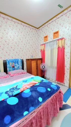a bedroom with a bed with a blue comforter at Penginapan Syariah Dhifa Indonesian only in Bukittinggi