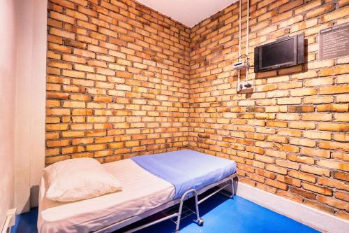 a small brick room with a bed and a tv at Bata Merah Boutique Hotel in Banting