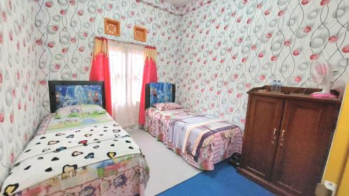 a bedroom with two twin beds and a dresser at Penginapan Syariah Dhifa Indonesian only in Bukittinggi