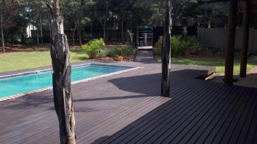a swimming pool with two trees on a wooden deck at Matori Lodge in Modimolle