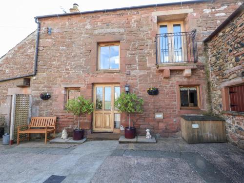a brick building with a wooden door and a bench at Swallow's Nest in Penrith