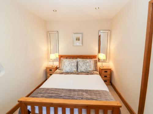 a bedroom with a wooden bed and two lamps at Swallow's Nest in Penrith