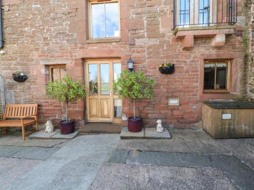 a brick building with two potted plants in front of a door at Swallow's Nest in Penrith