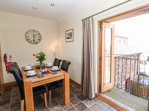 a dining room with a table and chairs and a clock at Swallow's Nest in Penrith