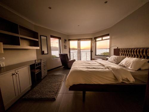 a bedroom with a bed and a desk and windows at Sunset Villa in Langebaan