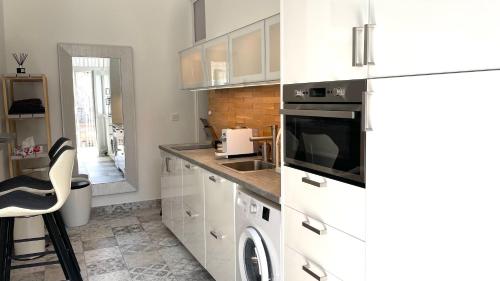 a kitchen with white cabinets and a sink and a dishwasher at Brand New sunny apartment on Andrássy street in Budapest
