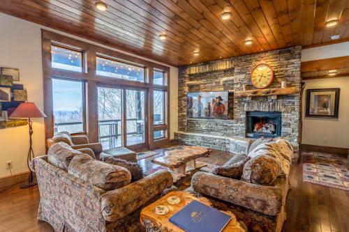 a living room with couches and a stone fireplace at Cardinal Perch in Beech Mountain