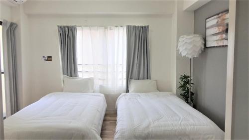Dos camas en una habitación pequeña con ventana. en Sun Park Heights, en Kobe
