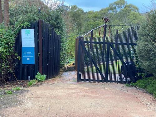a black gate with a sign in front of it at Delphi, Adelaide Hills Garden BnB in Mylor