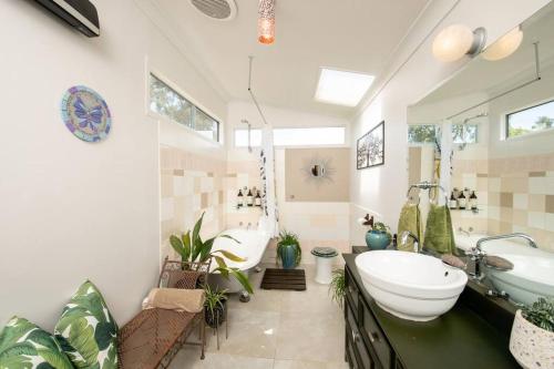 a bathroom with a large tub and a sink and a toilet at Delphi, Adelaide Hills Garden BnB in Mylor