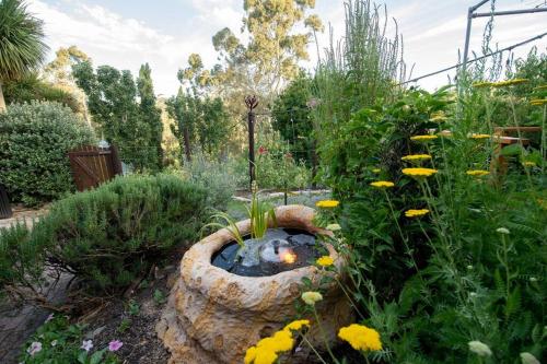 a garden with a rock bowl with a pond in the middle at Delphi, Adelaide Hills Garden BnB in Mylor