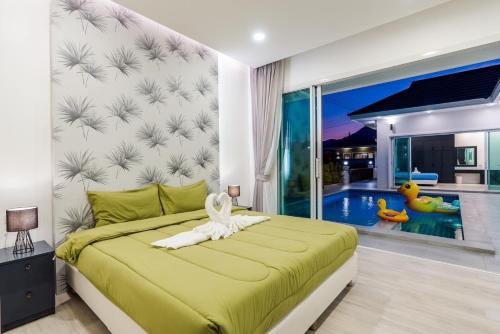 a bedroom with a green bed and a swimming pool at Dara pool villa in Ban Bang Liang