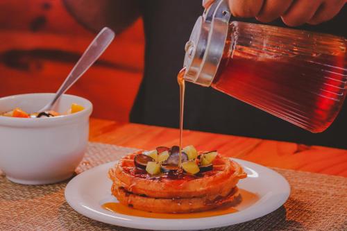 a person pouring syrup onto a stack of waffles at Hotel VillaOeste in Mossoró