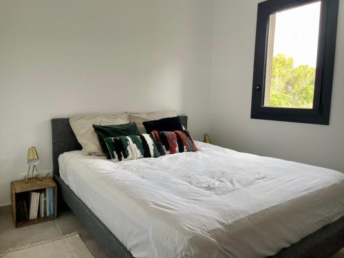 uma cama branca com almofadas num quarto em Rez de Jardin en pleine nature em Ventabren