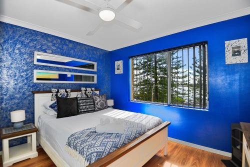 a blue bedroom with a bed and a window at Sandhurst 5 in The Entrance