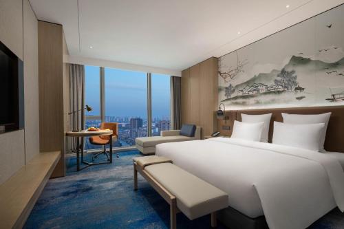 a bedroom with a large white bed and a living room at Pullman Huai'an in Huai'an