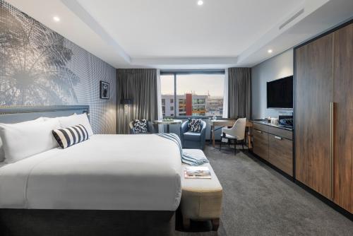 a hotel room with a bed and a television at Imagine Beach Road in Auckland