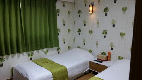 two beds in a room with green curtains and plants on the wall at Jeju R Hotel & Guesthouse in Jeju