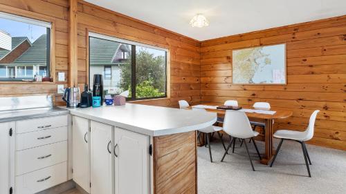 a kitchen with white cabinets and a table and chairs at Crystal Clear - Snells Beach Holiday Home in Snells Beach