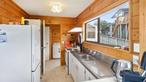 a kitchen with a white refrigerator and a window at Crystal Clear - Snells Beach Holiday Home in Snells Beach