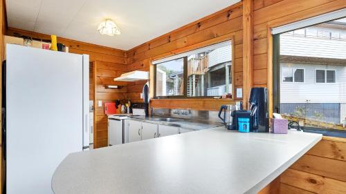 a kitchen with wooden walls and a white counter top at Crystal Clear - Snells Beach Holiday Home in Snells Beach