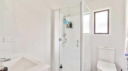 a white bathroom with a shower and a toilet at Crystal Clear - Snells Beach Holiday Home in Snells Beach