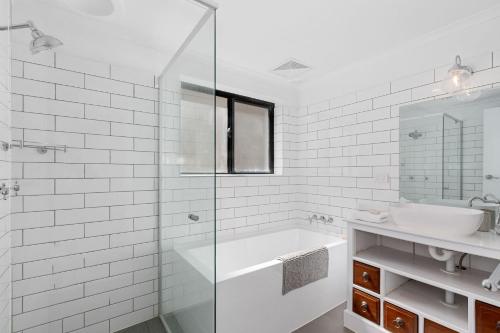 uma casa de banho branca com uma banheira e um lavatório em Villa Marina by the Sea - Pet Friendly em Kingscliff