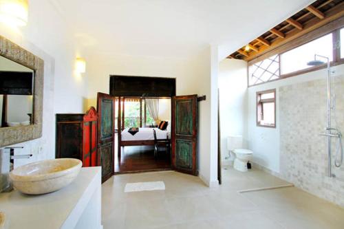 a bathroom with a sink and a bathroom with a tub at Villa Varuna in Legian