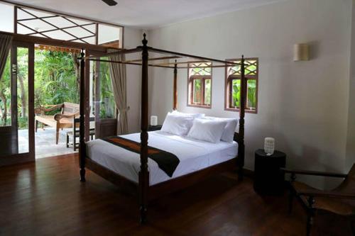 a bedroom with a canopy bed and a patio at Villa Varuna in Legian